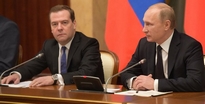 Poetin spreekt de regering toe, naast hem premier Medvedev