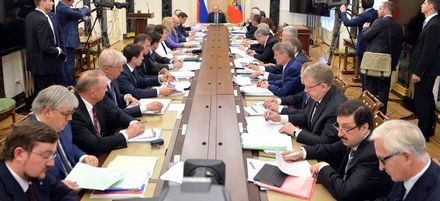 de tientallen leden van de raad, gezeten aan een ovalen tafel met een sprekende Poetin aan het hoofd