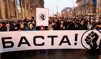 protesterende menigte achter een spandoek met 'basta'