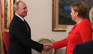 Poetin schudt handen met Merkel